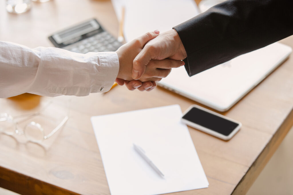 Gold coast buyers agent shaking hands with a client over a desk with papers